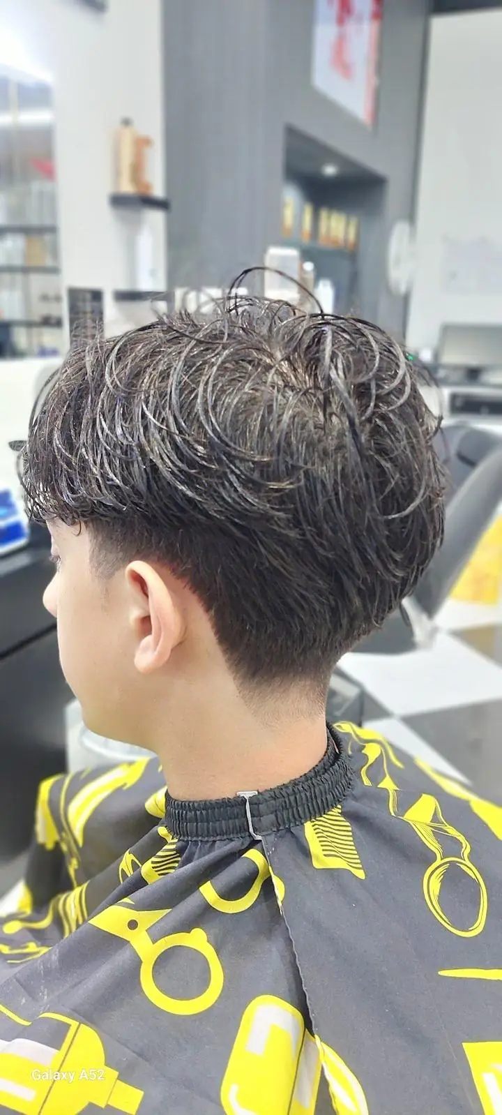 The finished cut: a taper with a textured curly top, done at the shop